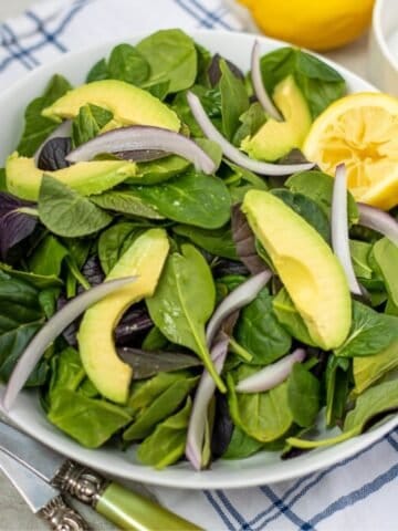 Bowl of Baby Spinach with lemon, avocaodo, and onion.