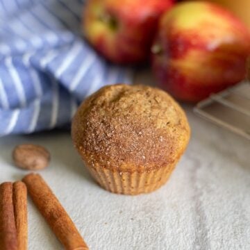 Applesauce muffin next to apples and cinnamon stick