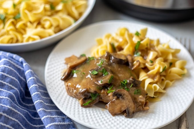 White Plate with Instant Pot Pork Chops, mushroom gravy and buttered noodles