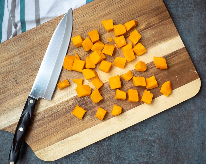 Cutting board with cubed butternut squash.