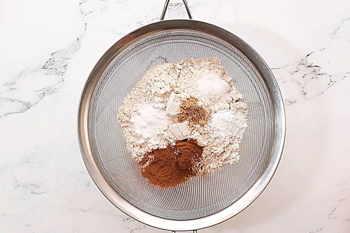 Metal sifter with flour, cinnamon, nutmeg and baking powder. 