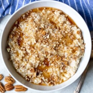 Bowl of slow cooker oatmeal topped with maple syrup and nuts