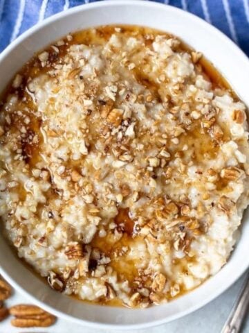 Bowl of slow cooker oatmeal topped with maple syrup and nuts