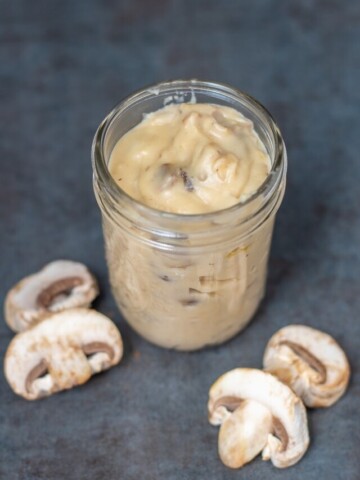 Jar of homemade condensed cream of mushroom soup next to button mushrooms