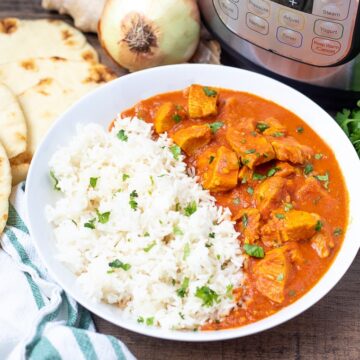 Bowl of Instant Pot Butter Chicken with rice next to Instant Pot
