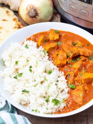 Bowl of Instant Pot Butter Chicken with rice next to Instant Pot