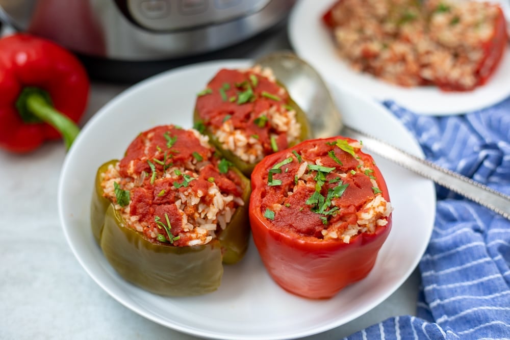 Stuffed peppers on a plate next to the Instant Pot.