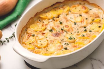 Baked Scalloped potatoes in whtie baking dish.