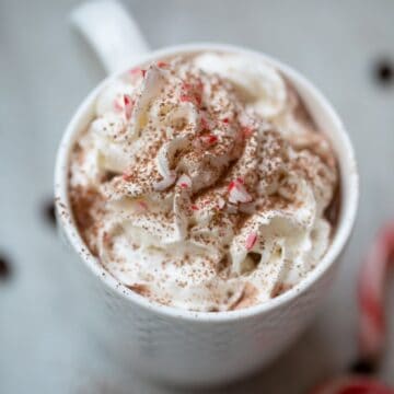 Close up of mug of hot chocolate topped with whipped cream and crushed peppermints.