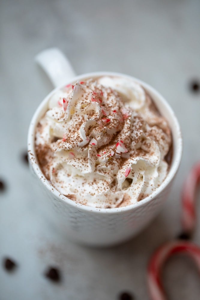 Mug of hot chocolate topped with whipped cream and crushed peppermints.