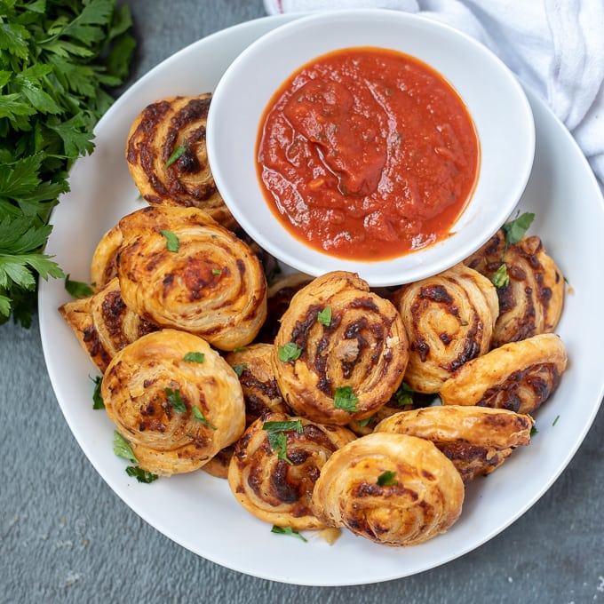 Platter of pizza rolls with bowl of marinara sauce.