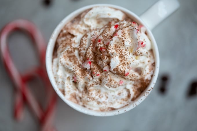 Mug of hot chocolate next to candy canes.