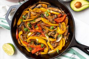 Vegetarian Fajita Mixture in cast iron skillet with lime and avocado off the side.