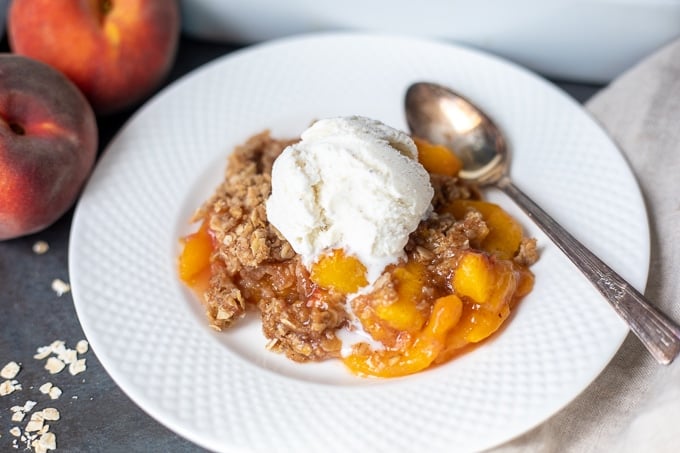Peach Crisp Dished out on White Plate with ice cream.