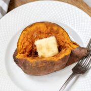 Instant Pot Sweet Potato on white plate topped with butter and cinnamon sugar