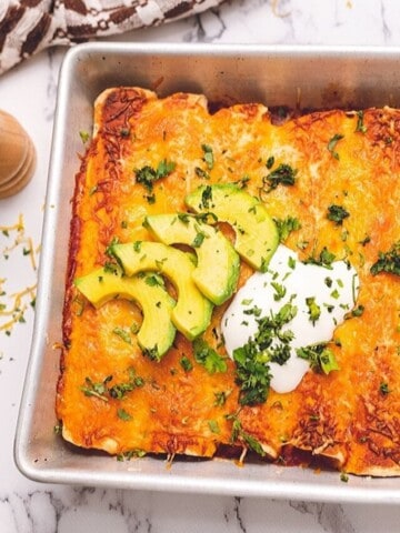 Baked Chicken Enchiladas topped with avocado and sour cream