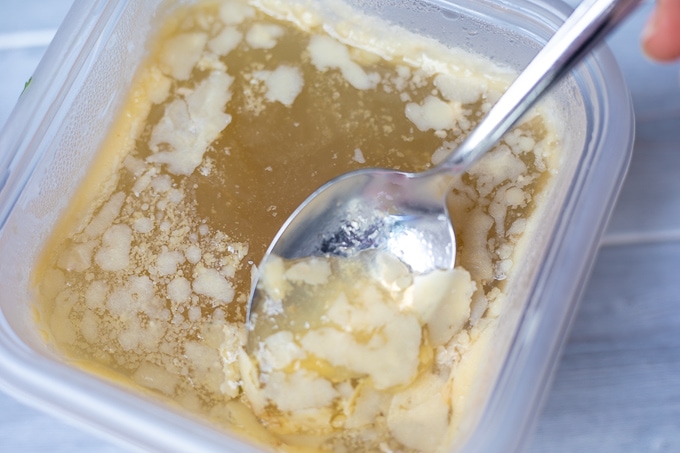 Spoon scraping off fat from chicken broth