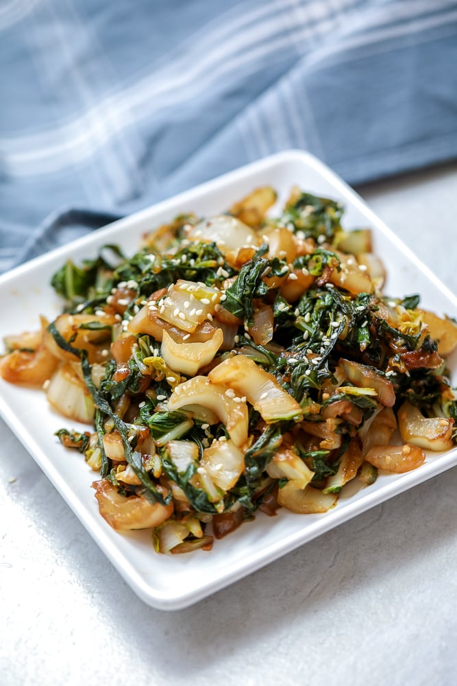 Stir Fried Bok Choy on white plate topped with sesame seeds.