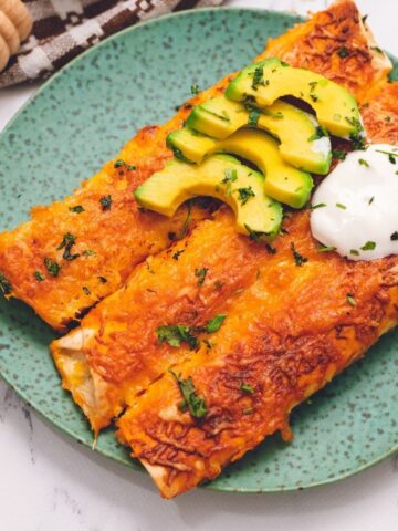 Chicken Enchiladas on plate topped with avocado