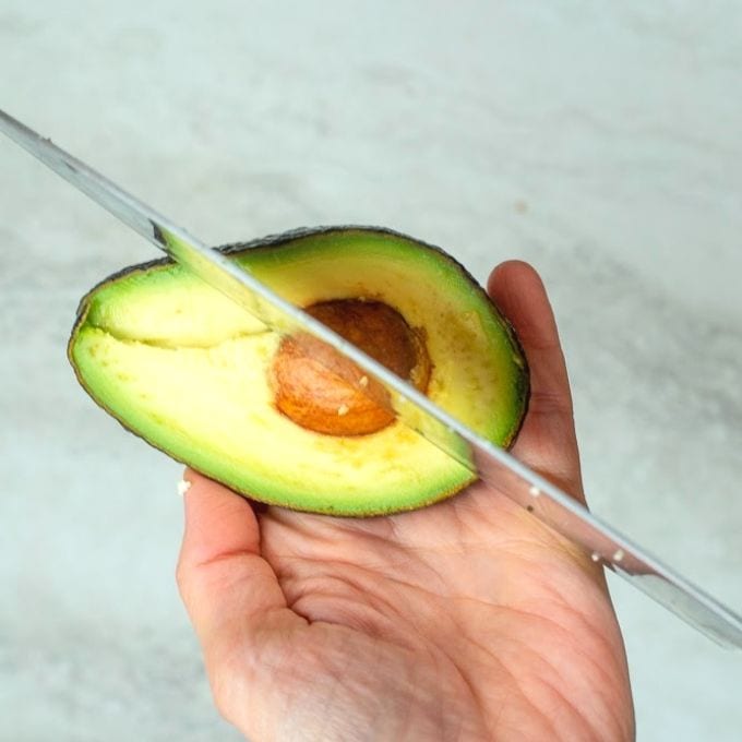 Cutting avocado with chef's knife.