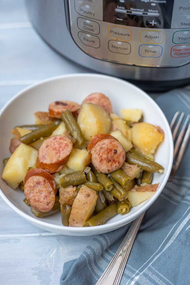 White Bowl with Smoked Sausage and Potatoes and Green Beans next to instant pot