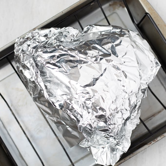 Ham wrapped in foil on roasting pan. 