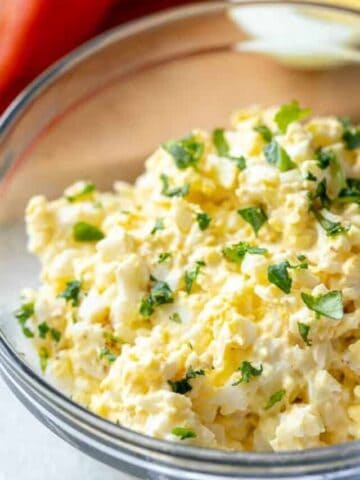 Bowl of egg salad topped with parsley.