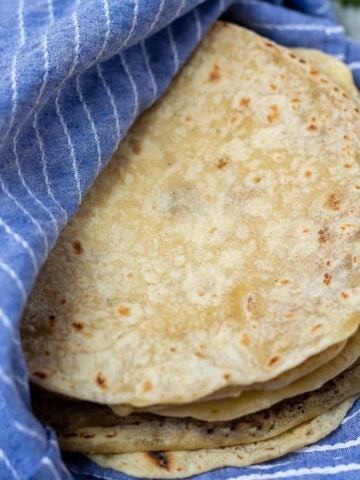 Stack of homemade tortillas in blue towel