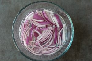 Red onions soaking in water.