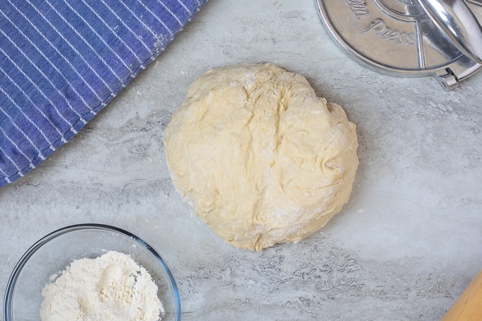 Tortilla dough next to small bowl of flour