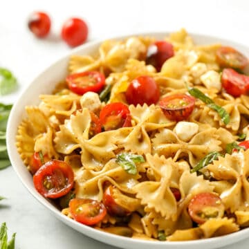 Close up of bowl of pasta salad with tomatoes and basil.