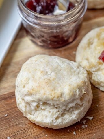 Buttermilk biscuit on cutting board next to jam