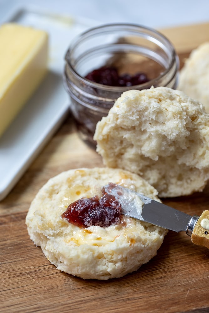 Biscuit cut open with butter, jam and drizzle of honey