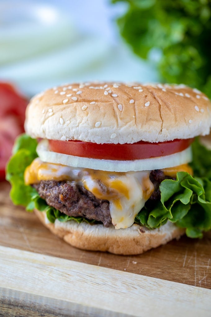 Cheeseburger assembled on a sesame seed bun with tomato, onion, and lettuce