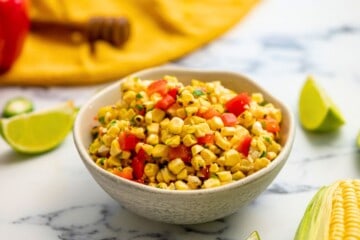 Bowl of grilled corn salsa with red pepper and honey lime dressing.