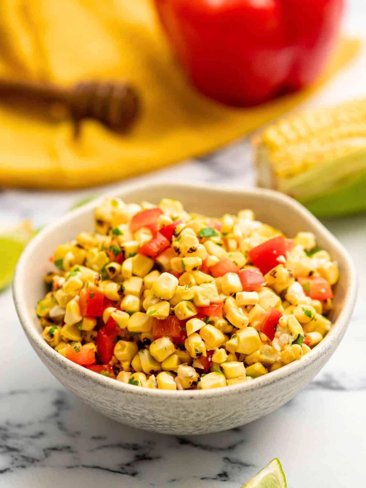 Bowl of grilled corn salsa with red pepper and honey lime dressing. 