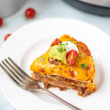 Slice of Instant Pot Mexican Lasagna on white plate with Instant Pot in background