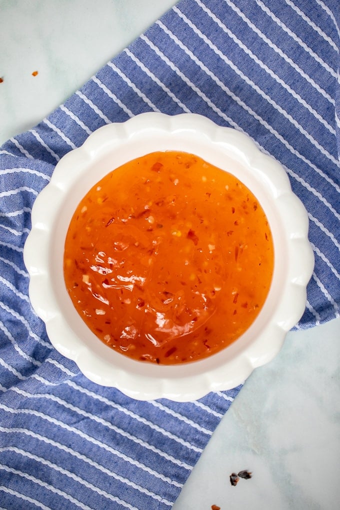 Sweet Chili Sauce in white bowl with blue napkin in background.