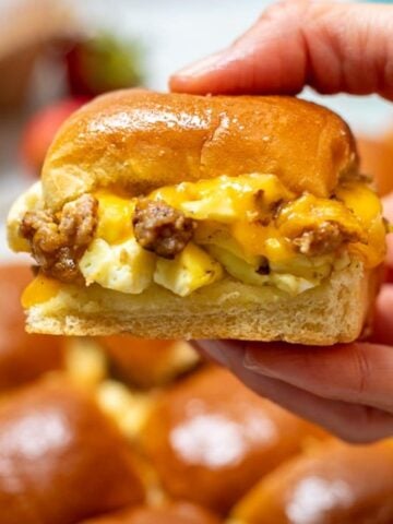 Hand holding breakfast sandwich made with sausage, eggs and cheese
