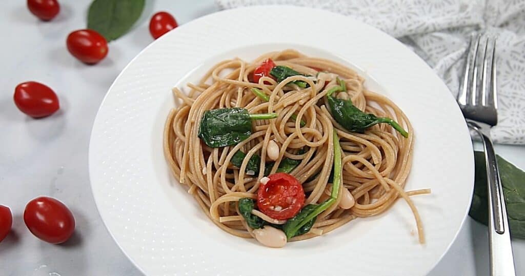 Bowl of spaghetti with tomatoes and spinach.