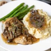 Chicken Marsala on white plate with mashed potatoes and green beans