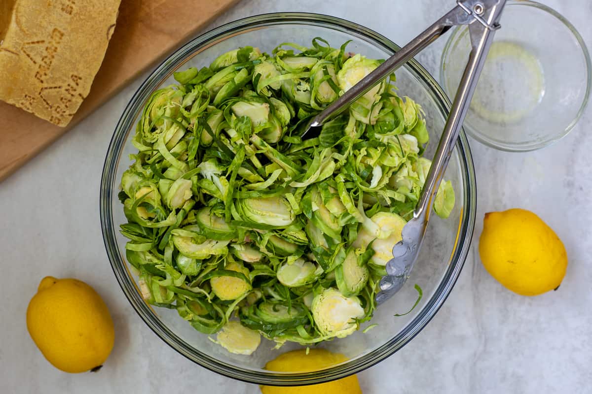 Brussels Sprouts tossed with lemon dressing in glass bowl.