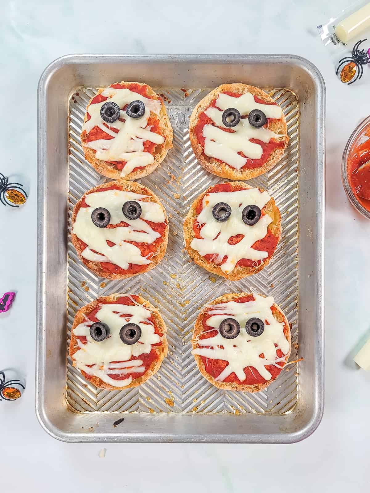 Mummy pizzas on baking sheet.