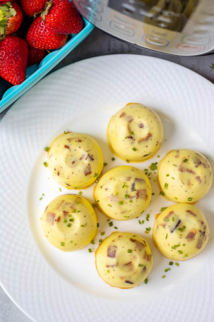 Bacon Swiss Egg Bites on white plate next to instant pot
