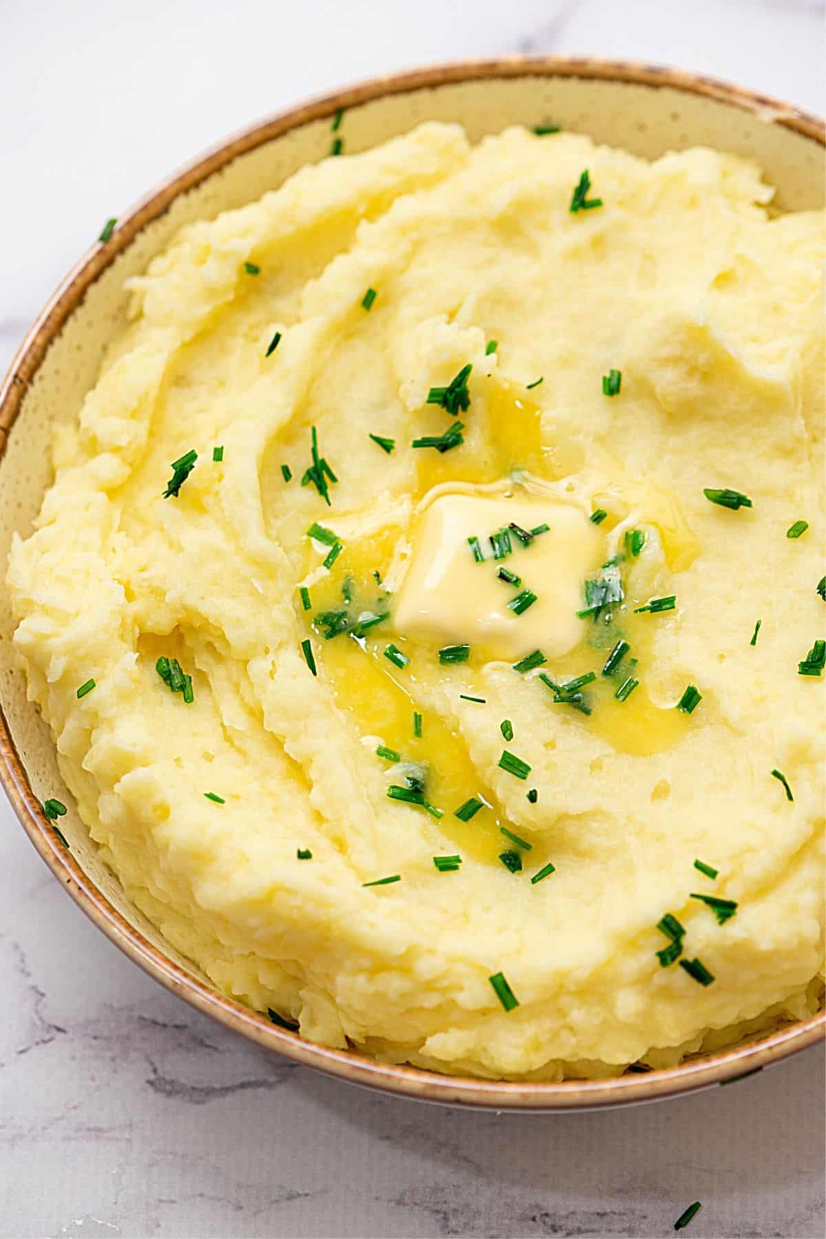 Bowl of Yukon Gold Mashed Potatoes topped with chives.