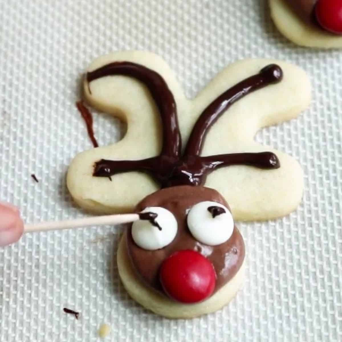 Using melted chocolate to make eyes on reindeer cookie