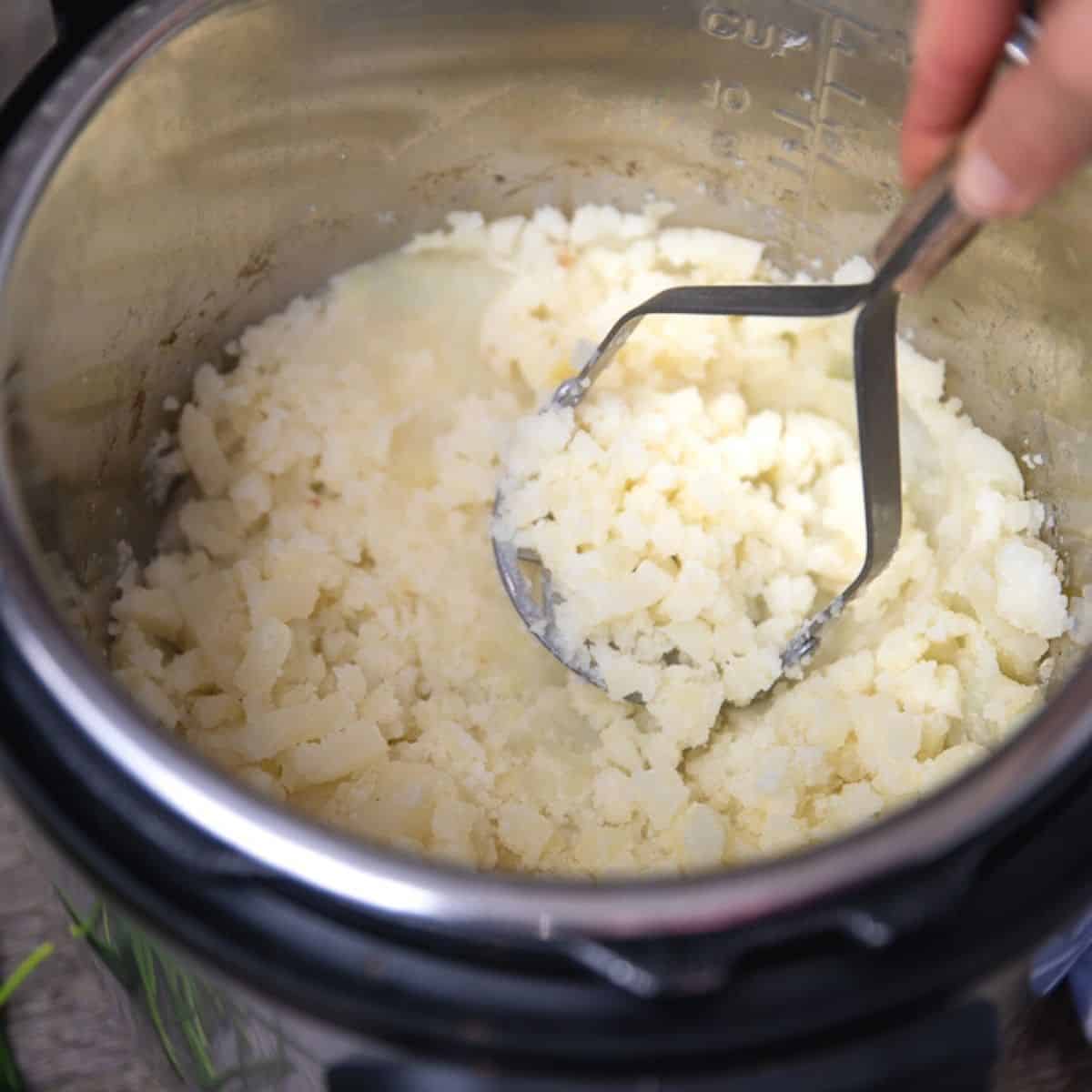 Potato Masher Mashing Up Cooked Potatoes in Instant Pot.