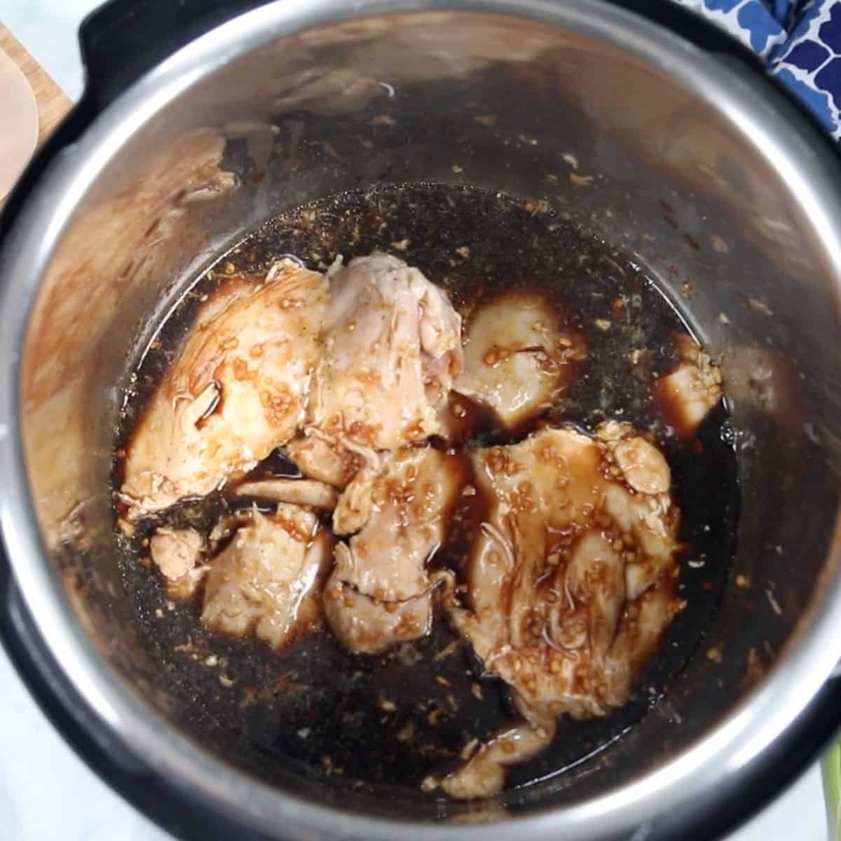 Seared chicken and teriyaki sauce in inner pot of pressure cooker. 