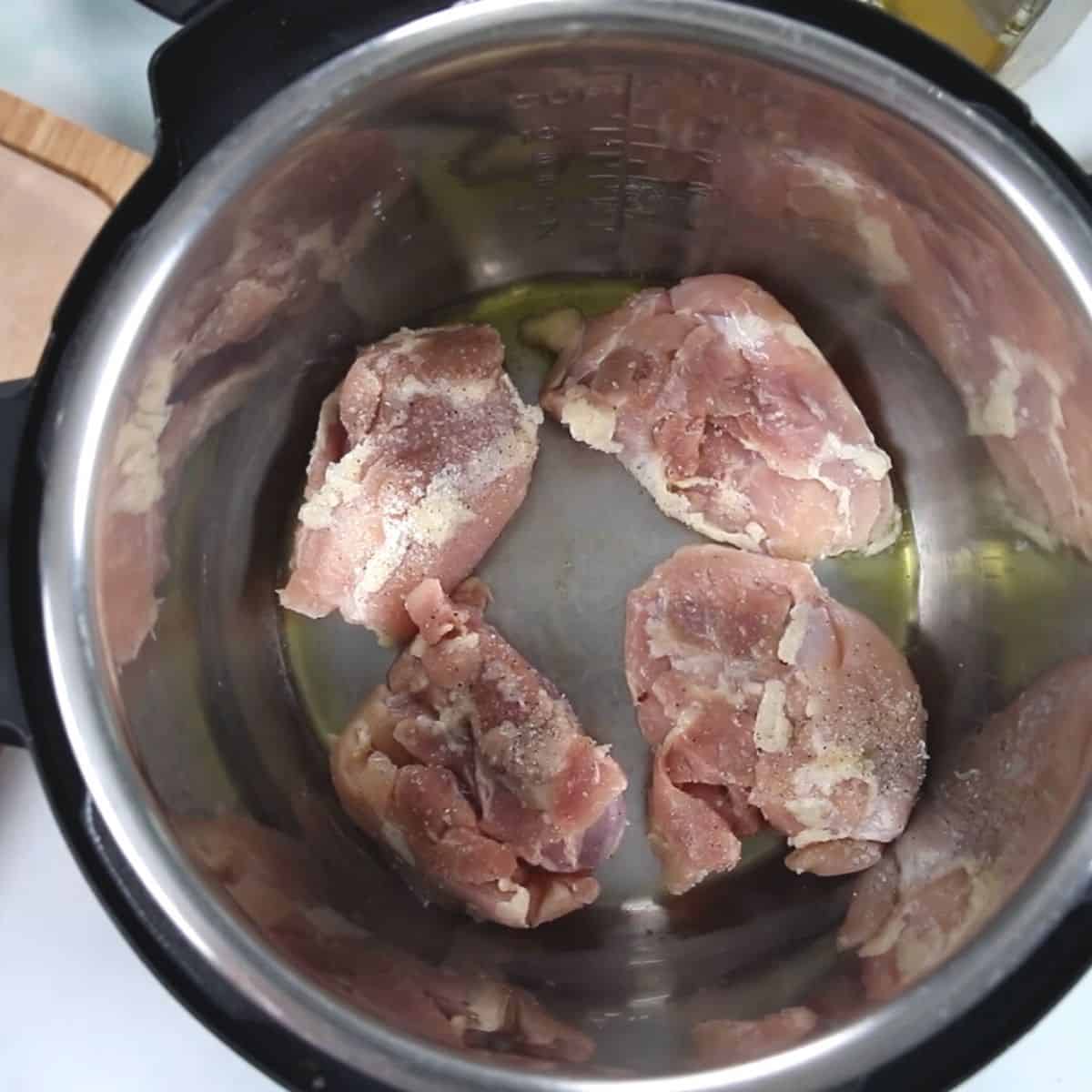 Chicken Thighs seasoned with salt and pepper in inner pot of instant pot. 