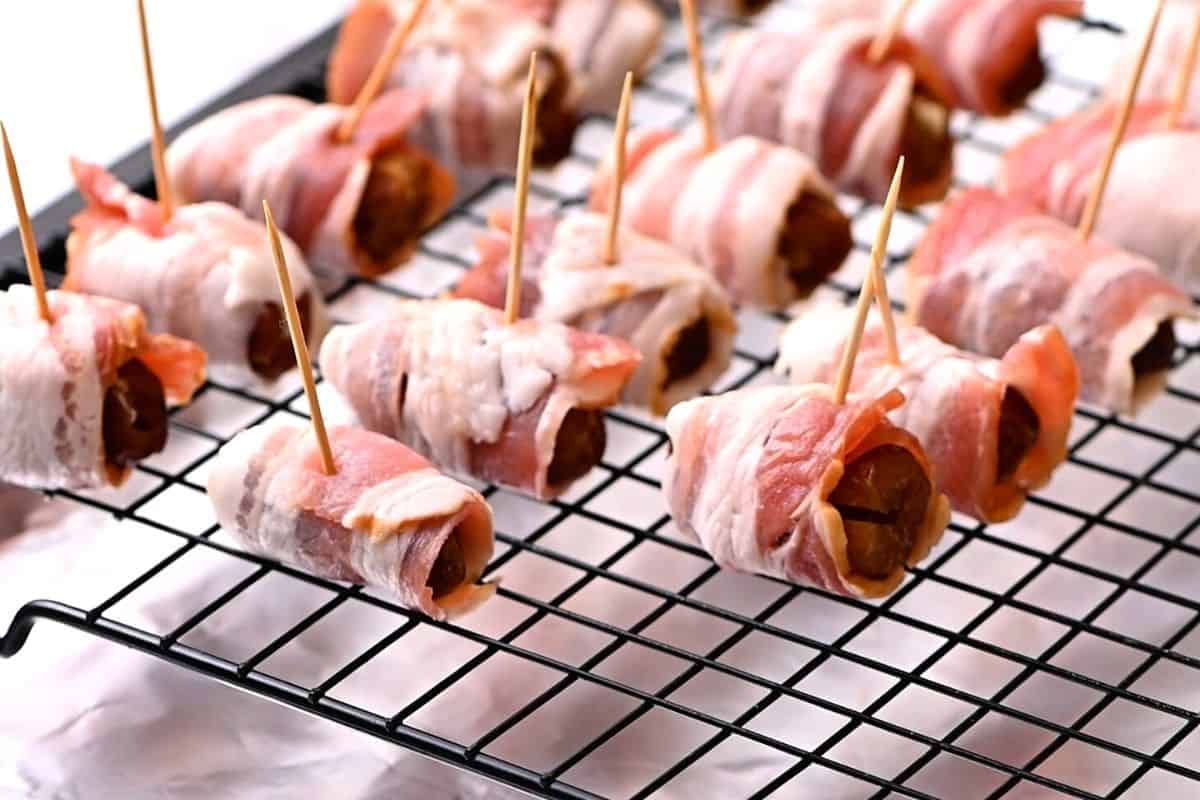 Stuffed Dates wrapped in bacon on baking sheet. 